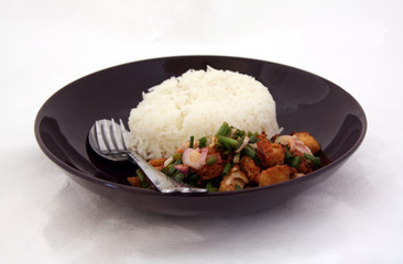 Fried chicken Spicy Salad with Rice in the black dish and cutlery, Food decoration with spring onion.