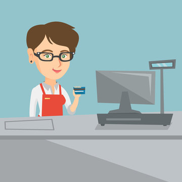 Caucasian smiling cashier standing at the checkout and holding a credit card. Young cashier making payment by credit card. Cashier showing a credit card. Vector cartoon illustration. Square layout.