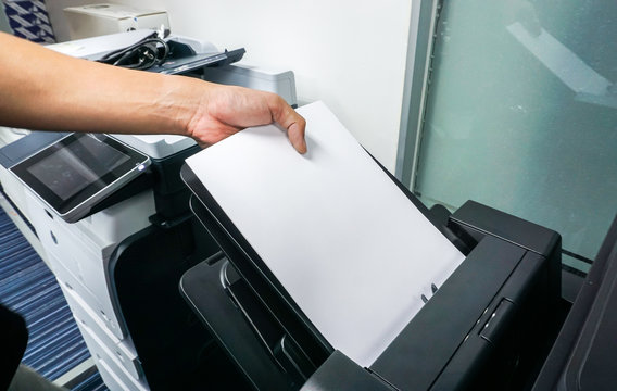 close up man put paper sheet into office printer tray