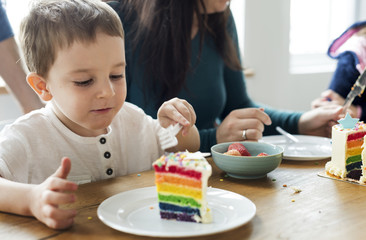 Little boy eating a rainbow colored cake