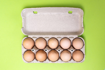 Chicken eggs in a cardboard box on a green background