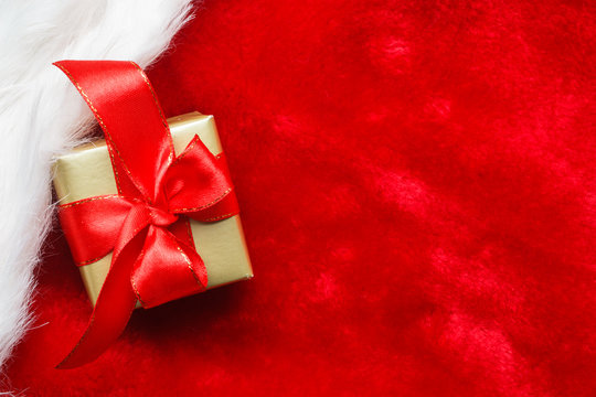 Small golden box with gift tied red bow