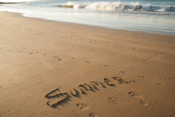 the word summer written in sand