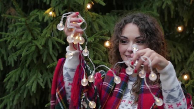 Christmas garland in the hands of a young woman on the background of the Christmas tree