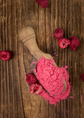 Portion of Raspberry powder on wooden background, selective focus
