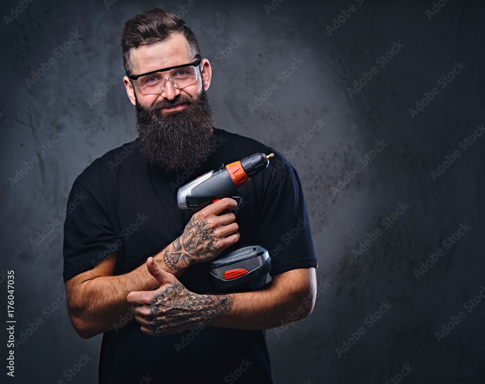 Wall mural a man holds a drill over grey background.