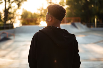 Back view of a young african man in earphones