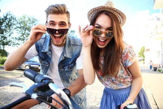 Happy Young Couple Going For A Bike Ride On A Summer Day In The City.They Are Having Fun Together.