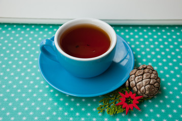 Blue cup with british tea with new year decor on green background with snowflakes.