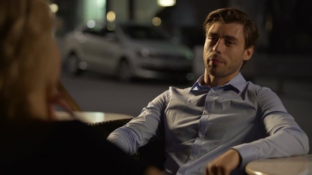 Handsome self-confident male flirting with woman in restaurant, evening date