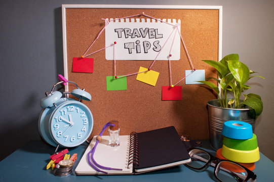 Table setup with alarm clock,note book,spectacle and text TRAVEL TIPS and Travel Plan.