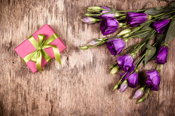 Pink gift box and eustoma. Romantic concept. Delicate flowers on a wooden background.