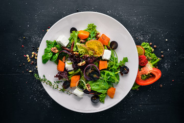 Pumpkin and fresh vegetables salad. Italian cuisine. Top view. Free space for text. On a wooden background.