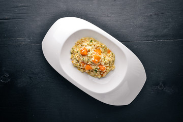 Risotto with pumpkin. Top view. Free space for text. On a wooden background.