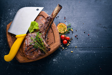 Steak on the bone. Top view. Free space for text. On a wooden background.