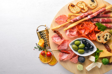 Cold snacks. Chopped sausage, bacon, olives, olives. Top view. Wooden background. Free space for text.