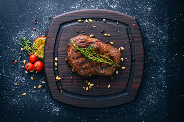 Veal steak with spices on the board. Top view. Free space for text. On a wooden background.