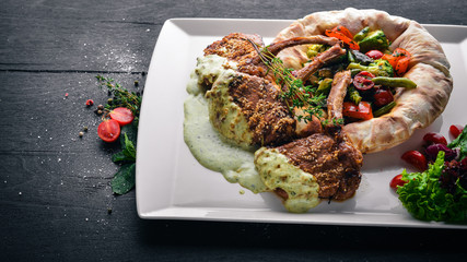 Veal steak on the bone. Grilled vegetables. Top view. Free space for text. On a wooden background.