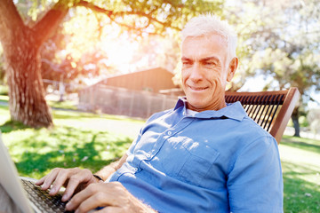 Senior man with notebook sitting in the park