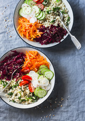 Fall vegetarian buddha bowl. Bulgur, spinach, beets, carrots, cucumbers, tomatoes, daikon - balanced healthy eating lunch. On a blue background, top view. Comfort autumn winter food