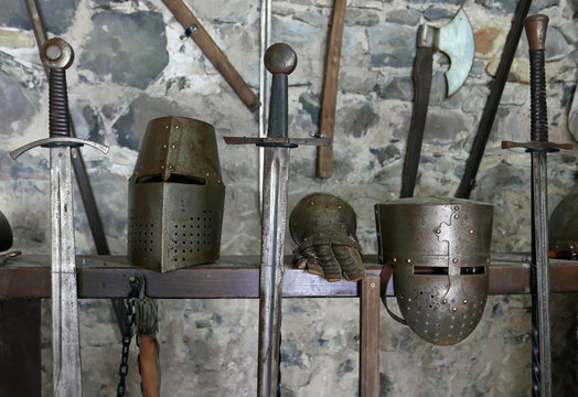 Ausstellung mittelalterlicher Schwerter und Helme vor einer Steinwand