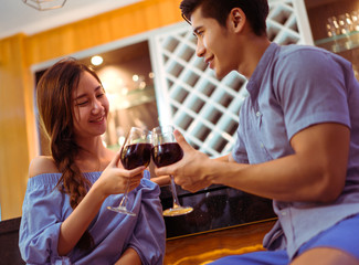 Young asian couple together man and woman clink glasses drink wine, cocktail in bar luxury party celebration clam relaxing in nightclub at pub