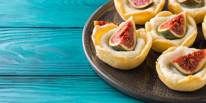 Tartlets with ricotta and figs on green wooden table. Mini treats