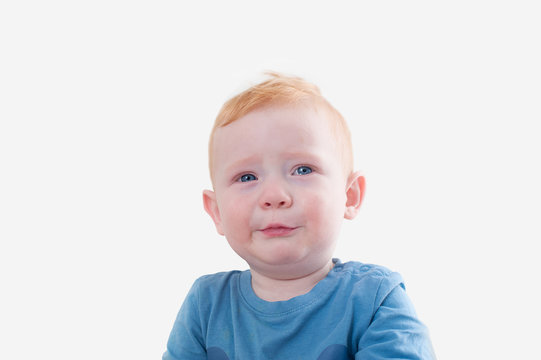 Crying redhead boy in blue tank top on the white background