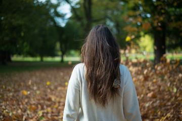 Falling leaves in autumn with long hair young woman in the park