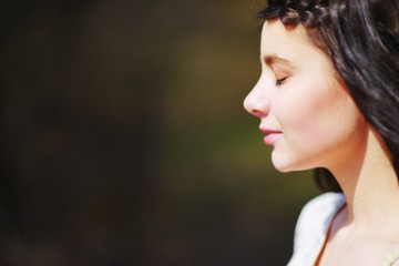 Naklejka premium wonderful profile of meditators cute pretty woman brunette with braided on the forehead with a pigtail with closed eyes on blurred background, close-up.