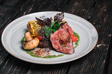 Grilled beefsteak with vegetable on dark wooden background