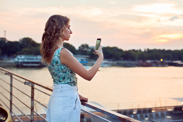 young, pretty woman on the riverside bridge with mobile phone