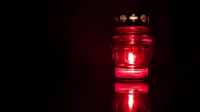 Timelapse of red memory lantern with trembling flame votive candle on dark mirror background