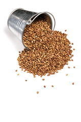Buckwheat is scattered on a white background from a bucket