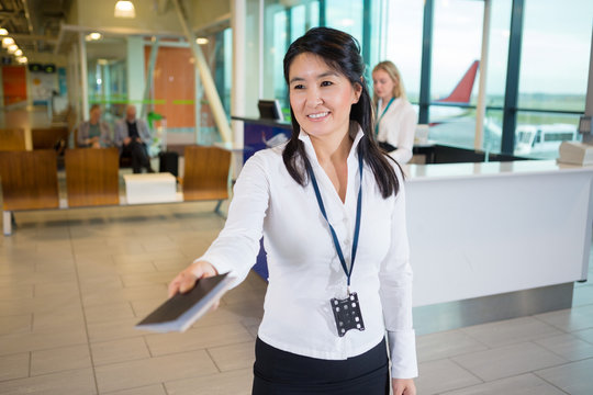 Smiling Staff Member Giving Passport At Airport Terminal