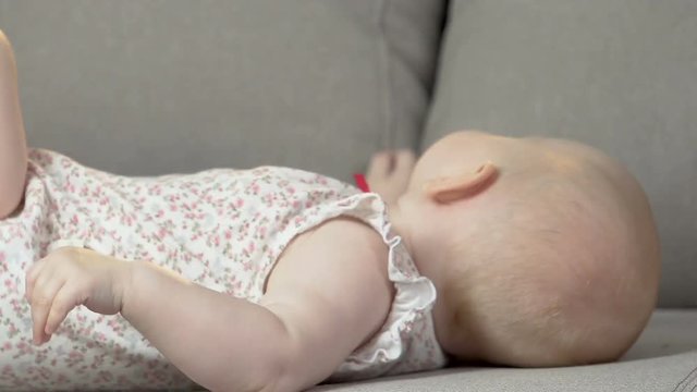 Baby lying on back on couch kicking arms and legs, energetic child, infancy