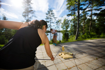 Woman Picking Up Wooden Block With Rope On Patio