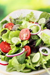 bowl of salad with vegetables and greens, with tomato, cucumber and onions