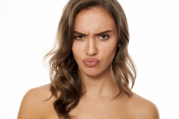 Obraz premium Portrait of beautiful young scowling woman on white background
