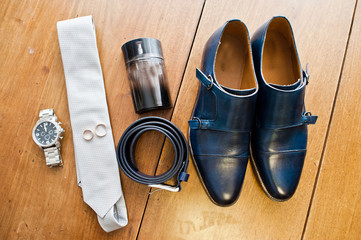 Fototapeta na wymiar Groom's white tie, silver watch, black leather belt, perfume and a pair of wedding boots.