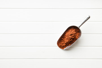 Dark cocoa powder in metal scoop.