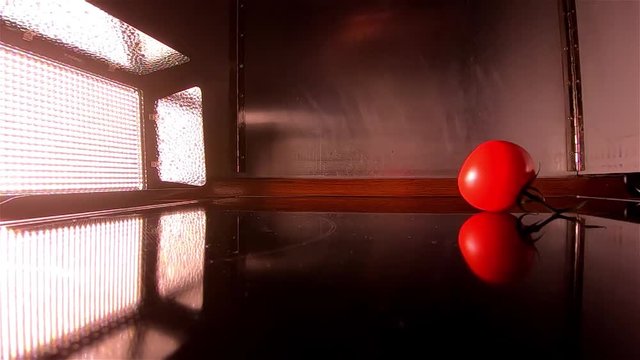 Floodlight lights up the falling of a tomato in slow motion