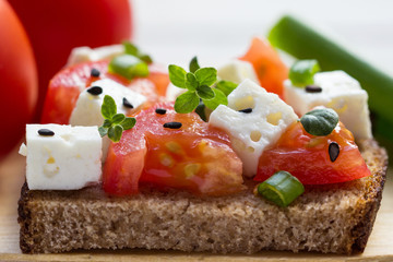 A delicious sandwich with cheese, tomatoes and thyme on a plate.