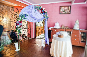 Wedding arch and table with present box on top of it. Two cakes on the background.