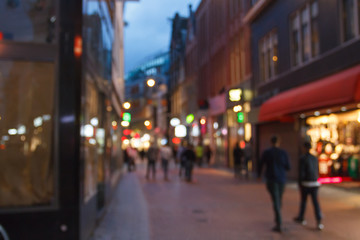 The urban landscape of the city at night with pedestrians out of focus.