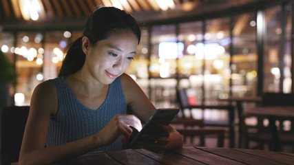Woman uses mobile phone in outdoor cafe
