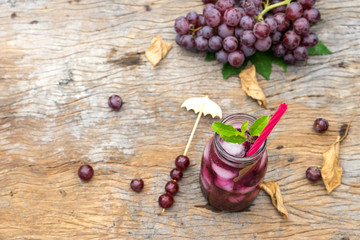 top view of grape juice in glass jar on old wood. dried leaf autumn concept. copy space for text