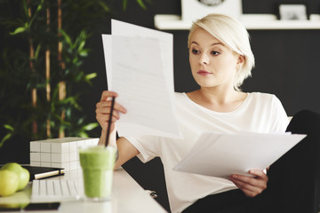 Concentrated businesswoman comparing documents at office
