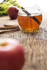 hot apple juice in glass with cinnamon on old wood. autumn food concept