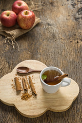 hot apple juice in cup with cinnamon and ground cinnamon on old wood. autumn food concept